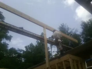 Carpenter setting a ridge beam over a new addition frame — Ice Dam Removal by Roofing Brothers in Osburn
