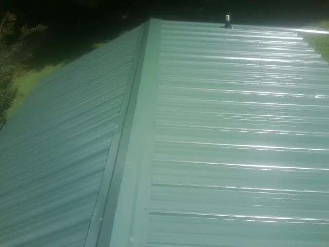 New green metal panels meeting at the ridge of a roof — Flat Roof Repair work by our crew in Osburn