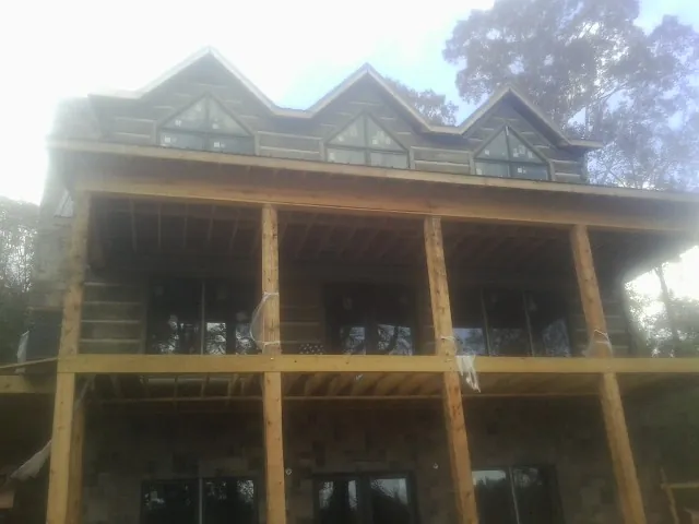 Dormers and porch framing on a large log home under construction — Roof Coating work by our crew in Osburn