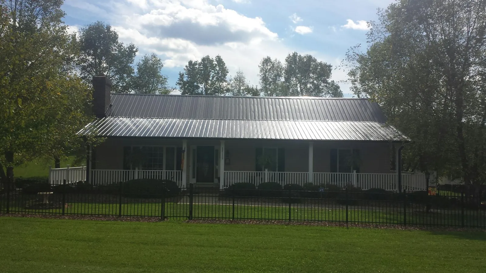 Gray metal roof on a brick ranch with a full width front porch — Gutter Guard Installation work by our crew in Osburn