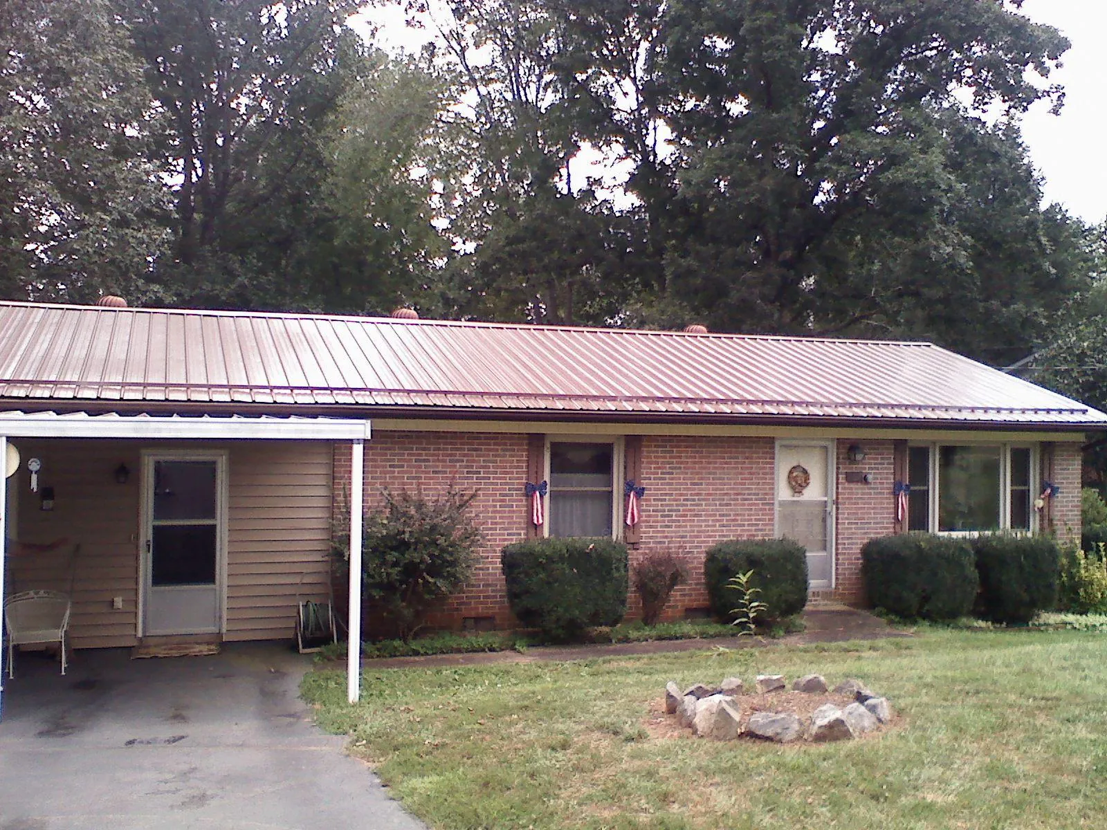 Bronze metal roof and carport on a brick ranch home — Roof Repair work by our crew in Osburn